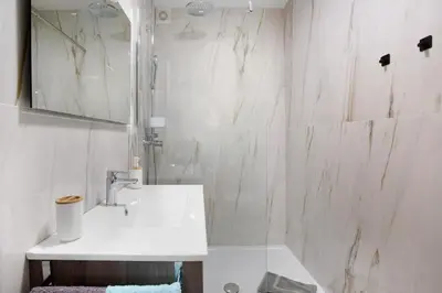 a white bathroom with a sink and a mirror at Casa De Pedra in Porto Santo