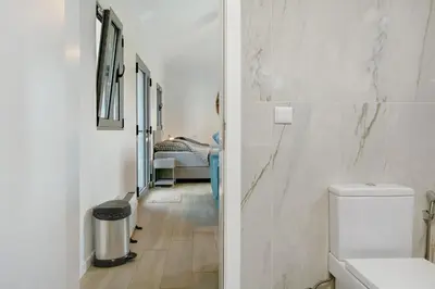 a white bathroom with a toilet and a hallway at Casa Do Vinho in Porto Santo