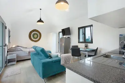 a living room with a blue couch and a kitchen at Casa Do Vinho in Porto Santo