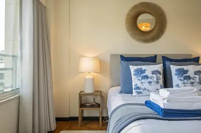 a bed with blue and white pillows and a mirror at Lavender - By Wehost in Funchal