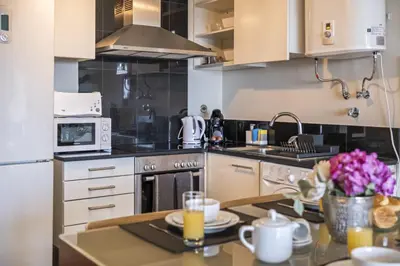 a kitchen with white cabinets and a table with flowers at Lavender - By Wehost in Funchal
