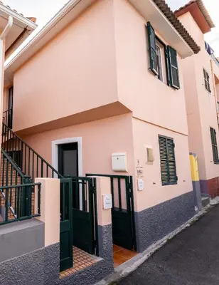 a house with green doors on a street at Fisherman's house in Porto Moniz