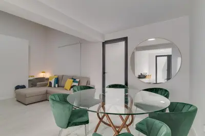 a dining room with a glass table and green chairs at Graça House in Machico