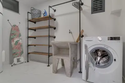 a laundry room with a washing machine and a chair at Graça House in Machico