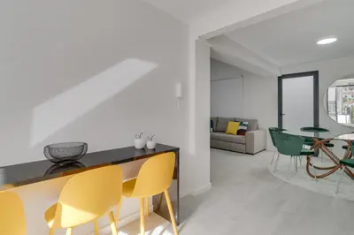 a kitchen and living room with yellow and green chairs at Graça House in Machico