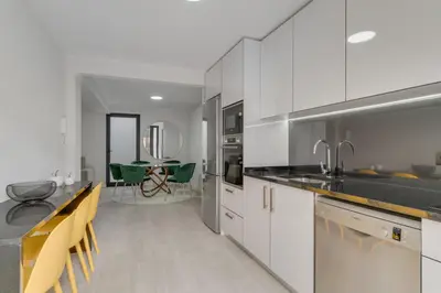 a kitchen with white cabinets and black counter tops at Graça House in Machico