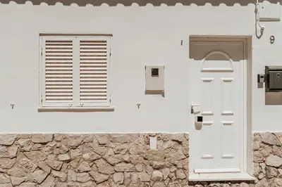 a white house with a window and a door at Charming traditional house in tiny, cozy village in Vale de Boi