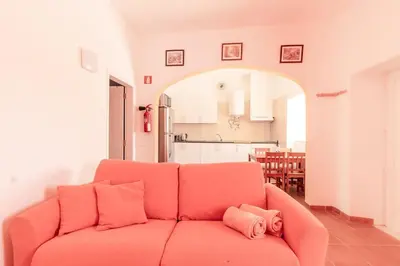 an orange couch in a living room with a kitchen at Charming traditional house in tiny, cozy village in Vale de Boi