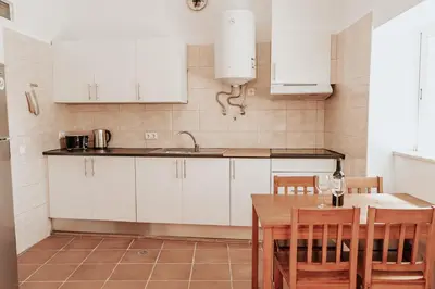 a kitchen with white cabinets and a wooden table at Charming traditional house in tiny, cozy village in Vale de Boi