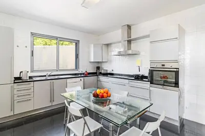 a kitchen with a glass table and white appliances at Villa Sol e Mar by Villa Plus in Caniço