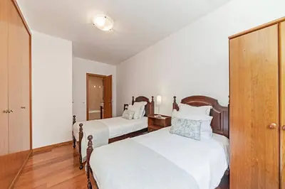 two beds in a room with white walls and wooden floors at Villa Sol e Mar by Villa Plus in Caniço