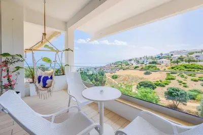 a balcony with white chairs and a table and a large window at Ocean Studio by ENDLESS SUN I modern comfort, sea view, wi-fi, parking, rooftop pool in Lagos