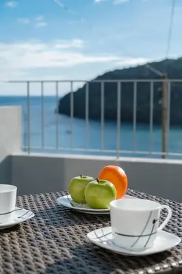 a table with plates of fruit and cups on a balcony at GuestReady - Machico sea view residence - B in Machico