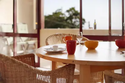 a dining room with a table and chairs and a large window at Casa Conny in Caniço