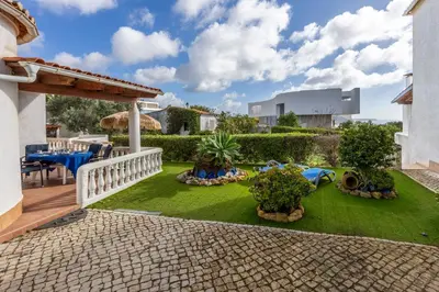a patio with a table and chairs on the grass at Seaside Retreat Casa Romana in Luz