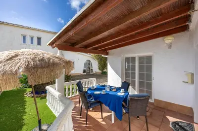 a patio with a table and a straw umbrella at Seaside Retreat Casa Romana in Luz