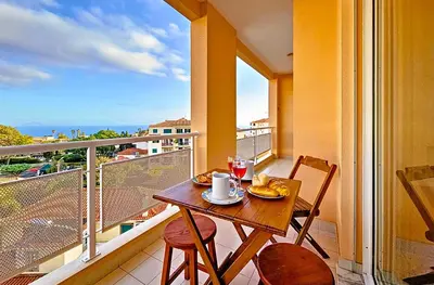 a table and chairs on a balcony with a view of the ocean at Caniço Center Apartment in Caniço