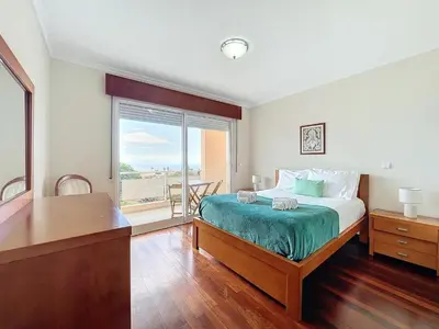 a bedroom with a bed and a large window at Caniço Center Apartment in Caniço