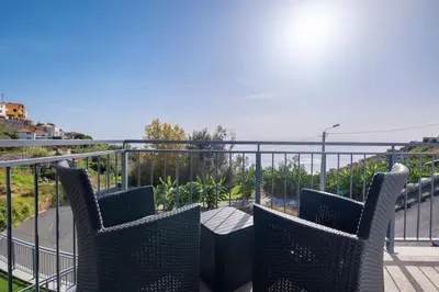 a patio with chairs and a table on a balcony at Yuri Big House in Ribeira Brava