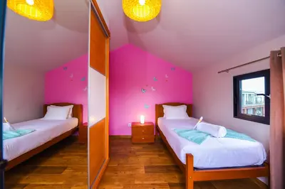 a bedroom with a large bed and a dresser at The Cozy Pink House in Ponta do Sol