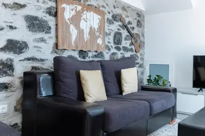 a blue couch in a living room with a stone wall at GuestReady - Leme Beach Breathtaking Views in Gaula