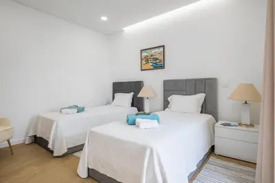 two beds in a bedroom with white walls and wood floors at Stunning view set in nature - Recanto of the sea in Ponta do Sol