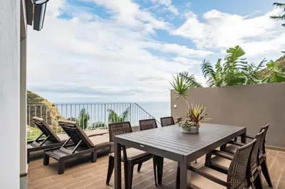a patio with a table and chairs on a balcony at Stunning view set in nature - Recanto of the sea in Ponta do Sol