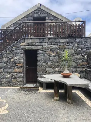 a stone building with a table with a potted plant on it at Cozy chalet with ocean view in Seixal