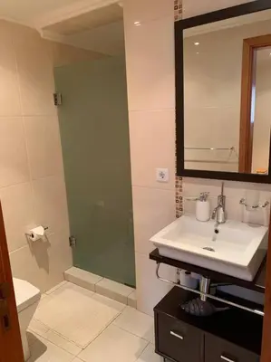 a bathroom with a sink and a mirror and a toilet at Cozy chalet with ocean view in Seixal