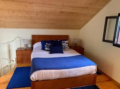 a bedroom with a large bed with blue pillows at Cozy chalet with ocean view in Seixal