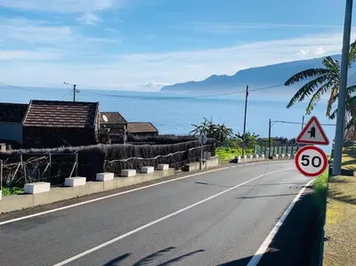 a road with a speed limit sign on the side of the road at Cozy chalet with ocean view in Seixal