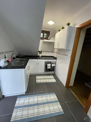 a small kitchen with white cabinets and a sink at Cozy chalet with ocean view in Seixal