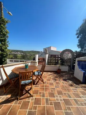 a patio with a wooden table and chairs on a roof at Casa das Escadinhas in Budens