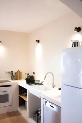 a white kitchen with a sink and a refrigerator at Casa das Escadinhas in Budens