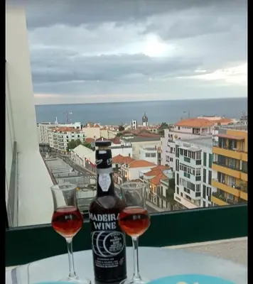 a bottle of wine and two glasses on a table with a window at Berna Apartment in Funchal