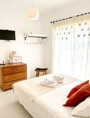 a white bedroom with a large bed and a television at Vila Fortaleza in Aljezur