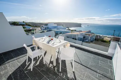 a white table and chairs on a balcony with the ocean at Vila Fortaleza in Aljezur