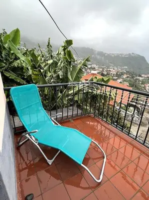 a blue chair sitting on top of a balcony at Kleines Haus am Meer in Arco da Calheta