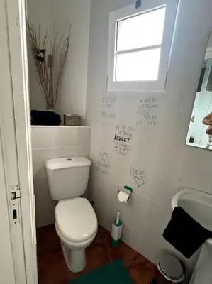 a bathroom with a toilet and a sink and a window at Kleines Haus am Meer in Arco da Calheta