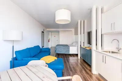 a living room with a blue couch and a bed at Marina Club Studio Apartment in Funchal