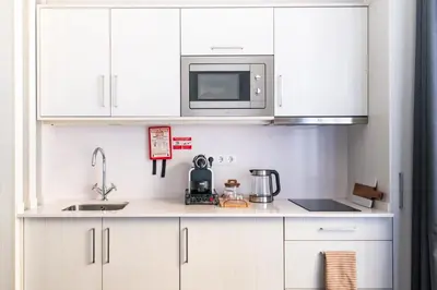 a kitchen with white cabinets and a microwave at Marina Club Studio Apartment in Funchal