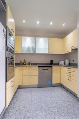 a kitchen with yellow cabinets and a white refrigerator at Monumental Palace in Funchal
