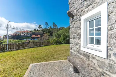 a window on the side of a stone building with a yard at Casa da Horta by Atlantic Holiday in Santa Cruz