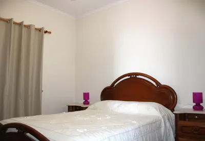 a bedroom with a bed and two tables with purple candles at Moradia Bela House in Santa Cruz
