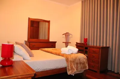 a bedroom with a bed with a dresser and a mirror at Moradia Bela House in Santa Cruz