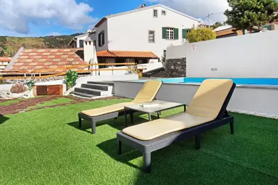 two chairs on a lawn with a pool at Casa Carreira in Ponta do Sol
