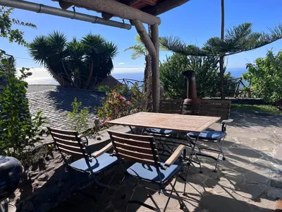 a wooden table and chairs on a patio with the ocean at Lucky Lemons - Boutique Houses Madeira - 2 in Estreito da Calheta