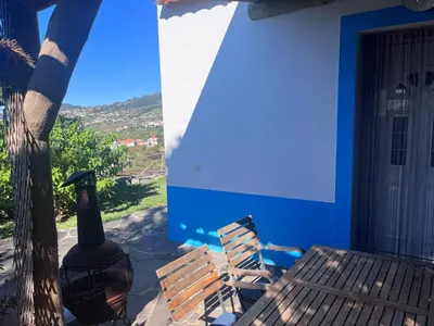 a blue house with a bench and a bottle of wine at Lucky Lemons - Boutique Houses Madeira - 2 in Estreito da Calheta