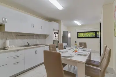 a white kitchen with a dining table and chairs at Lido Charm by Atlantic Holiday in Funchal