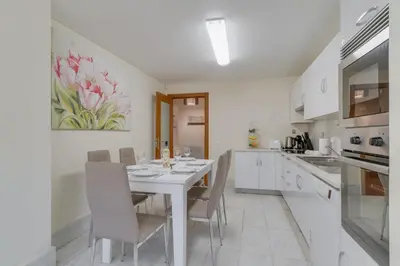 a white kitchen with a white table and chairs at Lido Charm by Atlantic Holiday in Funchal